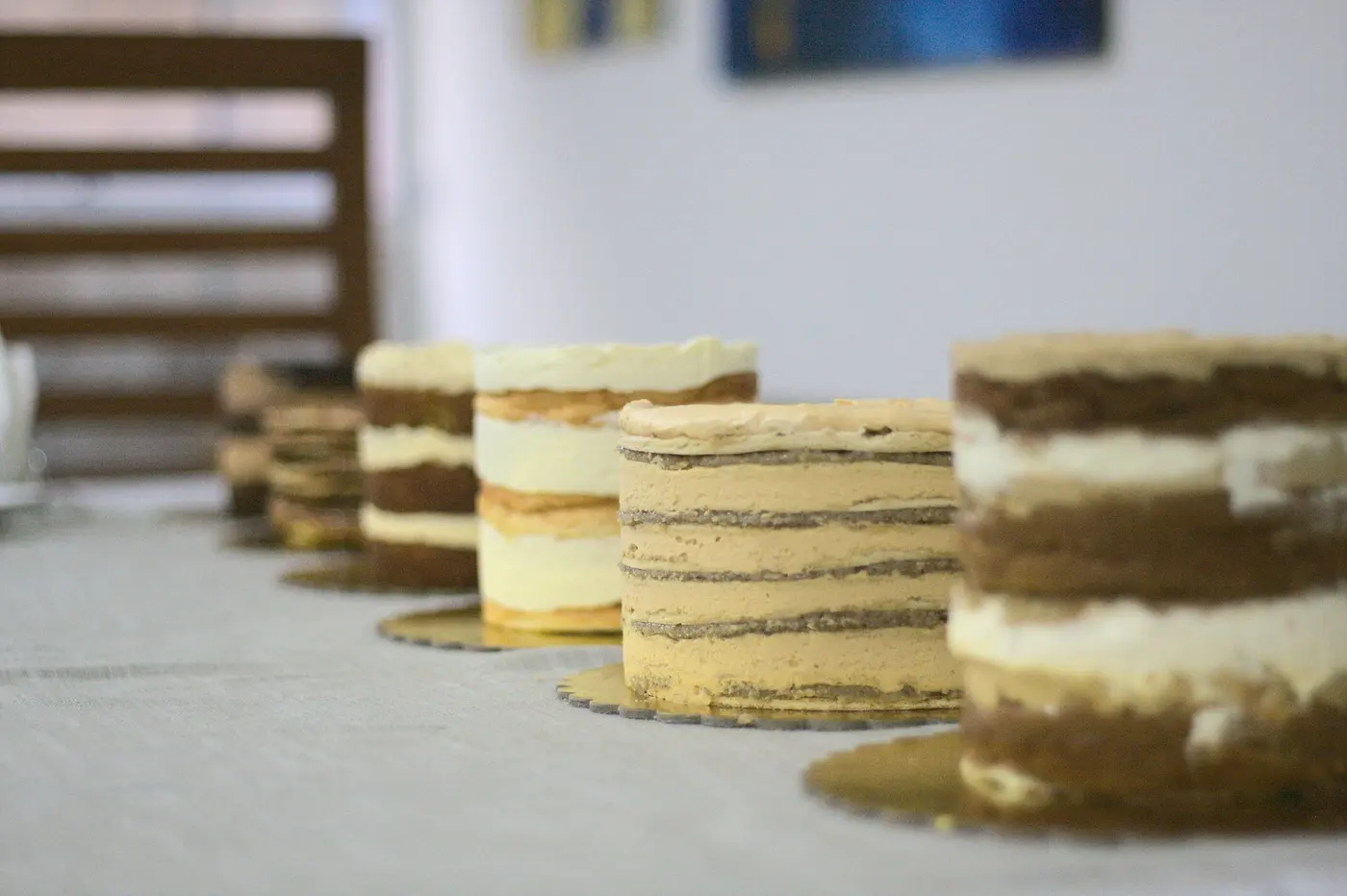 Fila de tortas sin cubrir sobre un mostrador, con los pisos de bizcocho y las capas de crema apiladas a la vista.