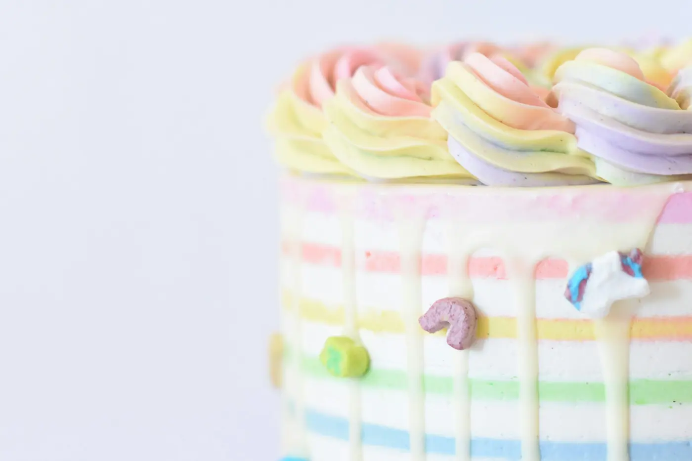 Torta cubierta de crema con rosetones en tonos pastel y rayas de colores en el costado.